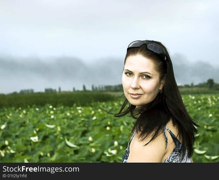 The girl against the river grown with green canes and lotuses. The girl against the river grown with green canes and lotuses