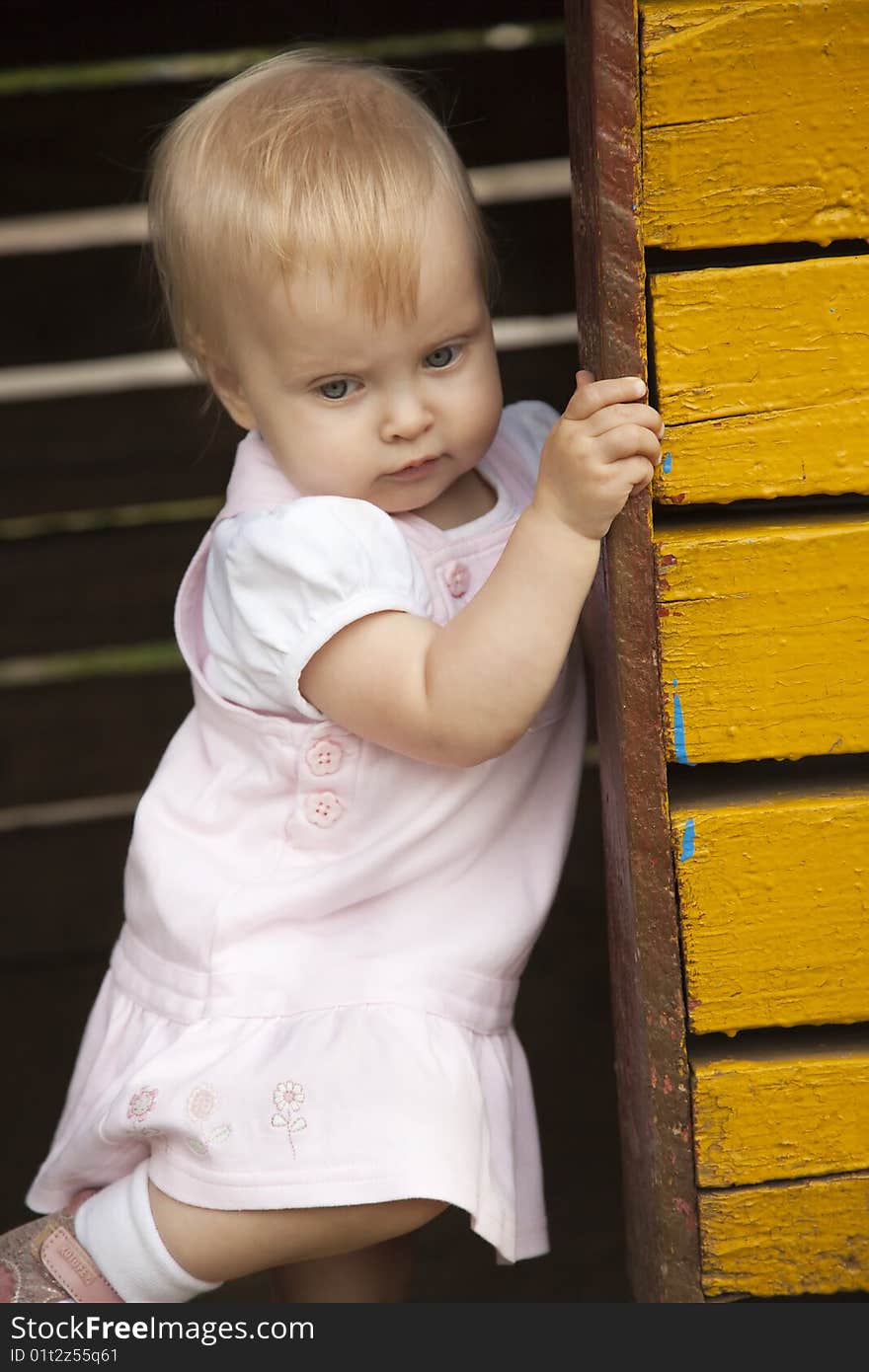 The little happy girl in rose dress. Playing in little house. The little happy girl in rose dress. Playing in little house