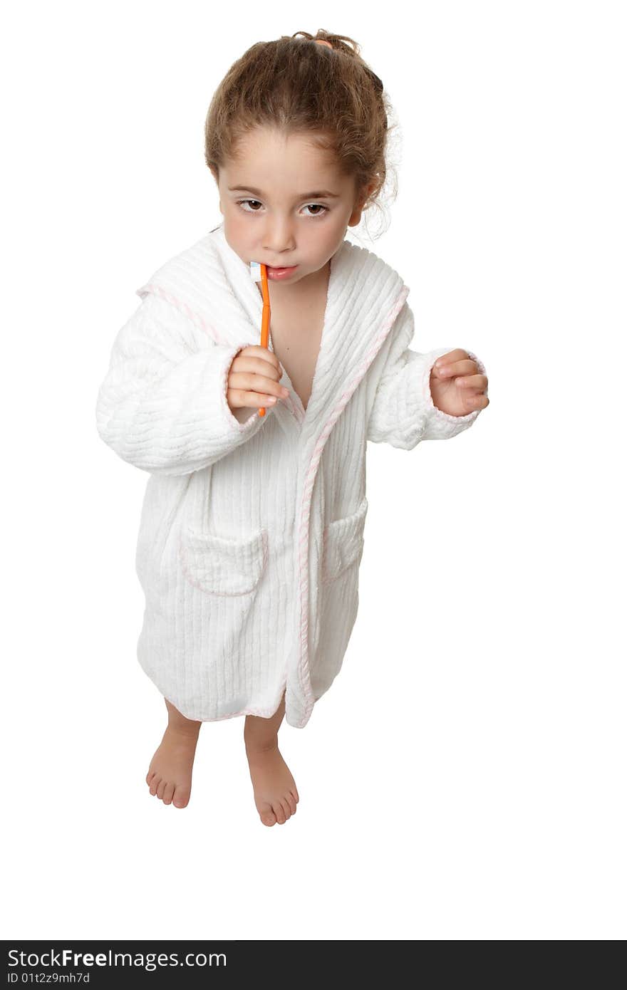 A small toddler girl in bathrobe is standing and brushing her teeth. A small toddler girl in bathrobe is standing and brushing her teeth