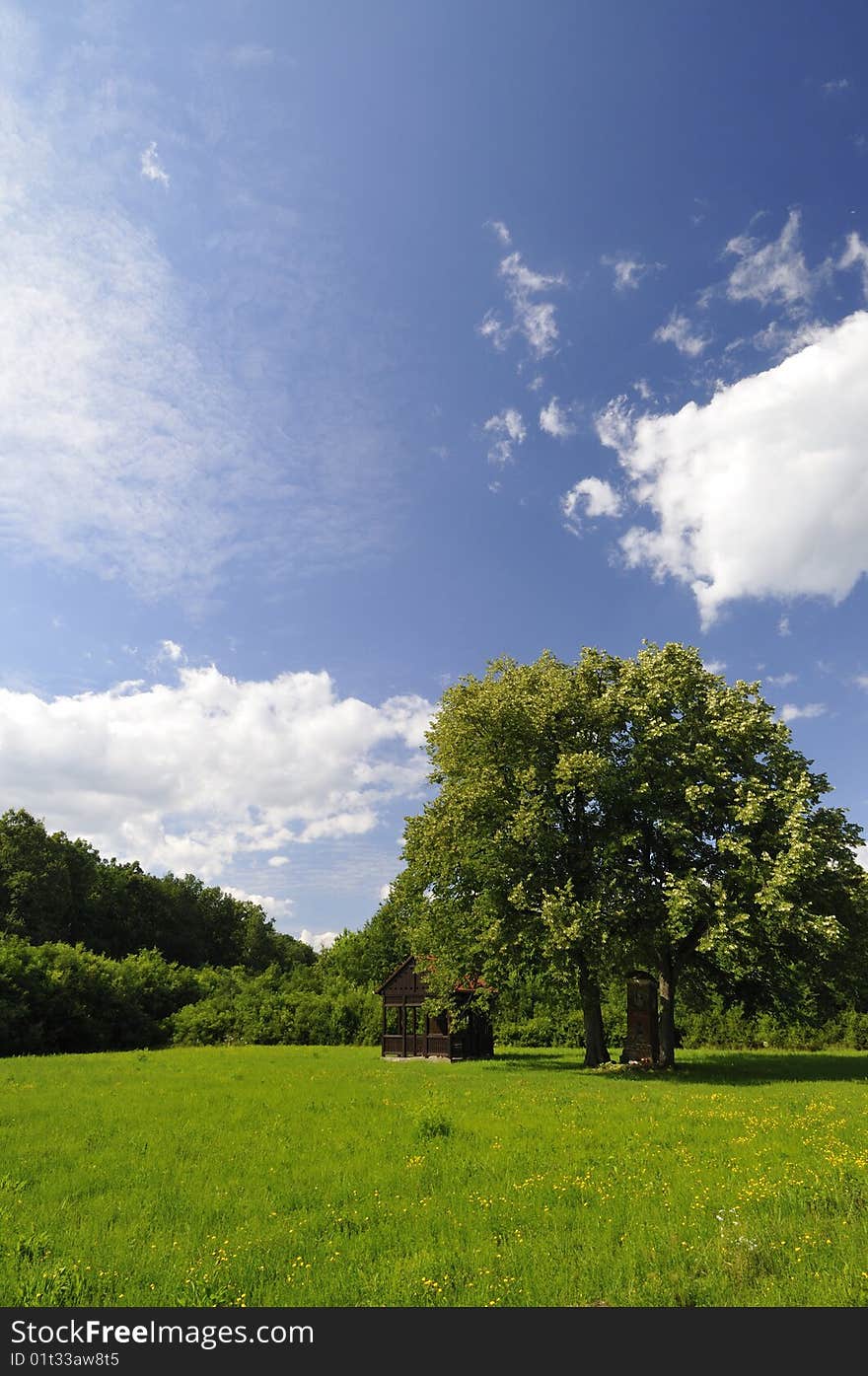 Green meadow with a wooden chapel under a picturesque sky. Green meadow with a wooden chapel under a picturesque sky