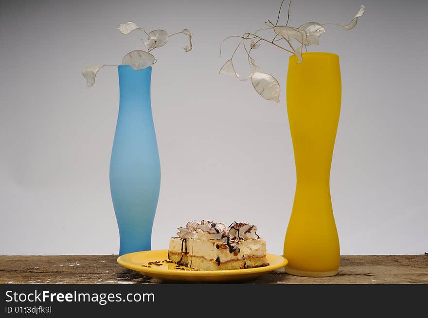 Close up with cakes  on yellow plate and two vases