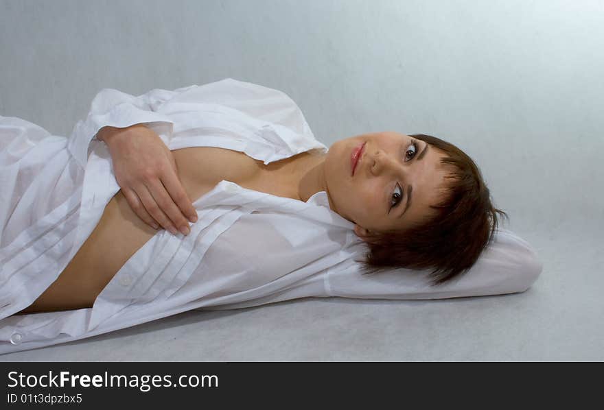 Portrait of girl who lies in a white shirt on an