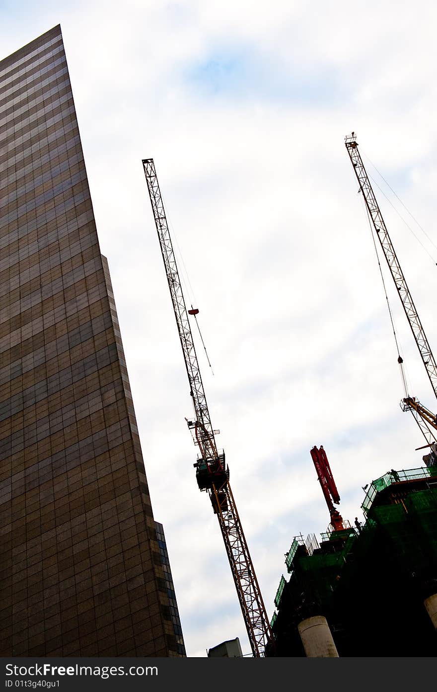 Construction cranes on site next to a skyscraper. Construction cranes on site next to a skyscraper.