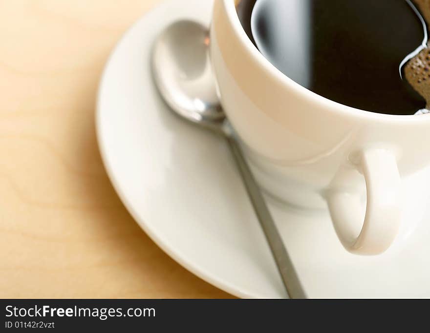 White cup of coffee with spoon on saucer