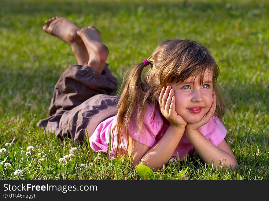 Little girl lying on the grass in the park, dreaming of something. Little girl lying on the grass in the park, dreaming of something