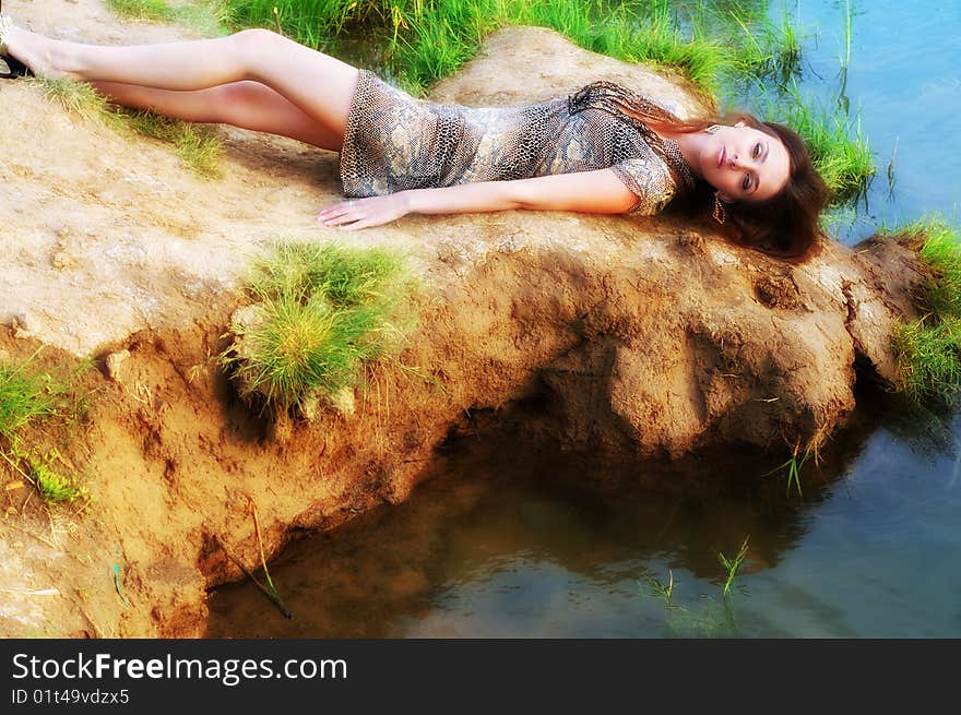 Beautiful sexual woman lays ashore near water. Beautiful sexual woman lays ashore near water