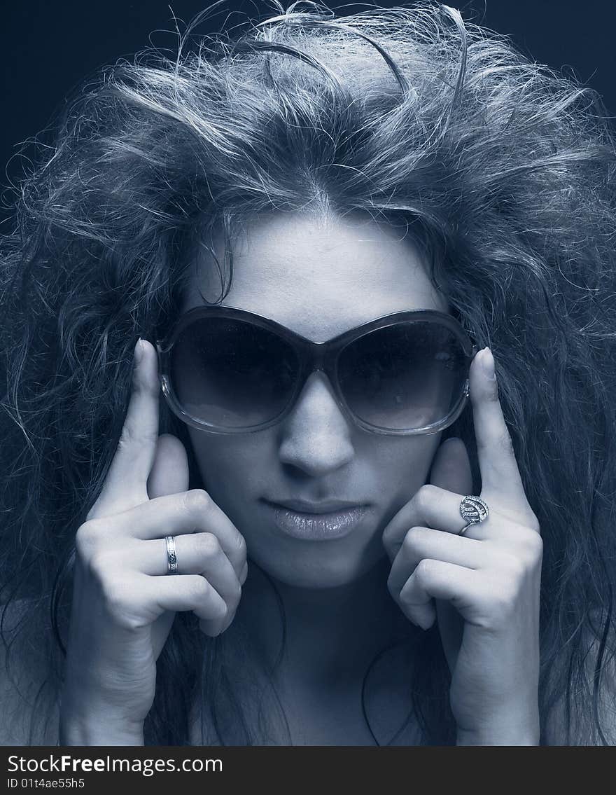 Portrait of young woman in sunglasses on the dark background