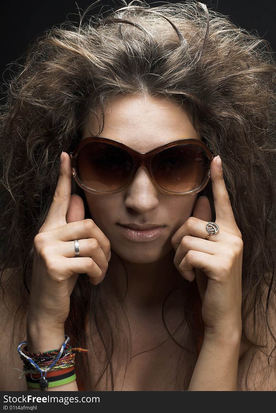 Portrait of young woman in sunglasses on the dark background