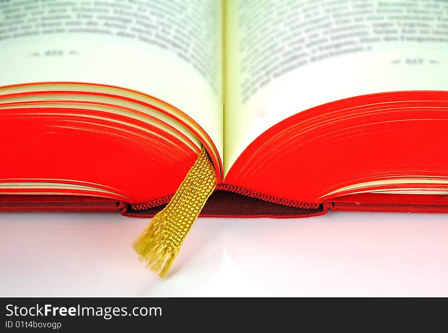 A flipped hardcover book with a golden bookmark. A flipped hardcover book with a golden bookmark.