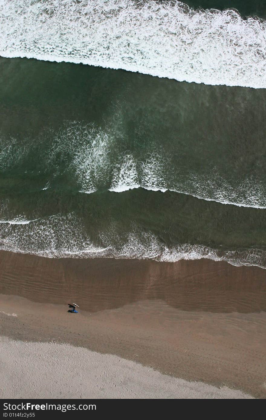 Two Surfers Walking Along The Beach