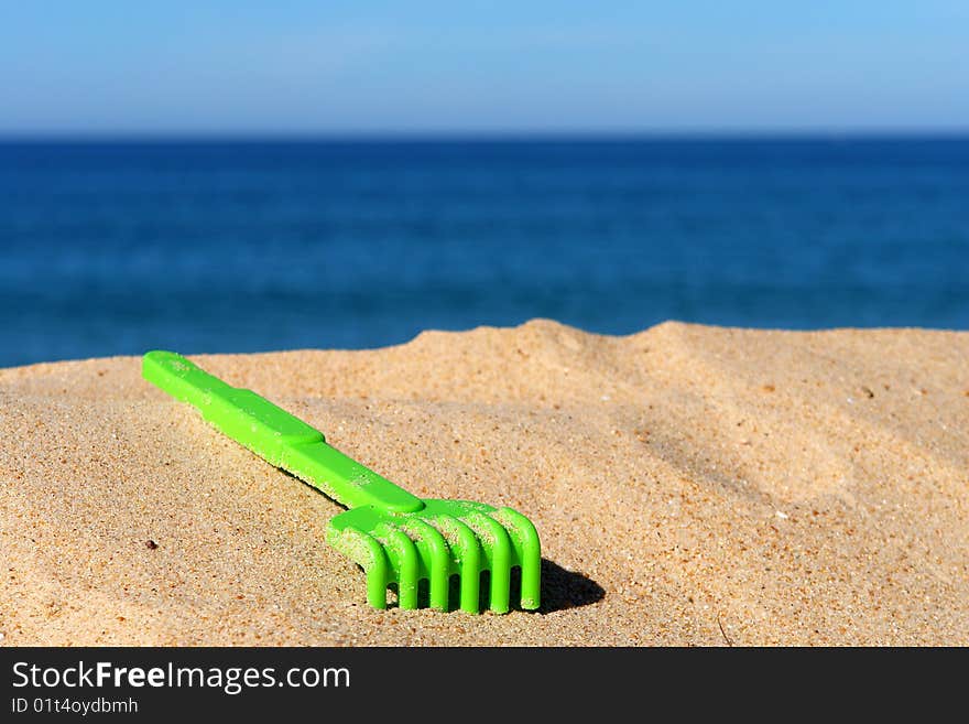 Child green toy on the sand beach.