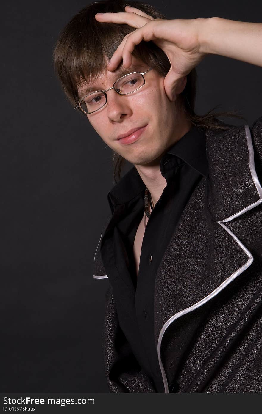 Portrait of young thinking man with glasses, black background