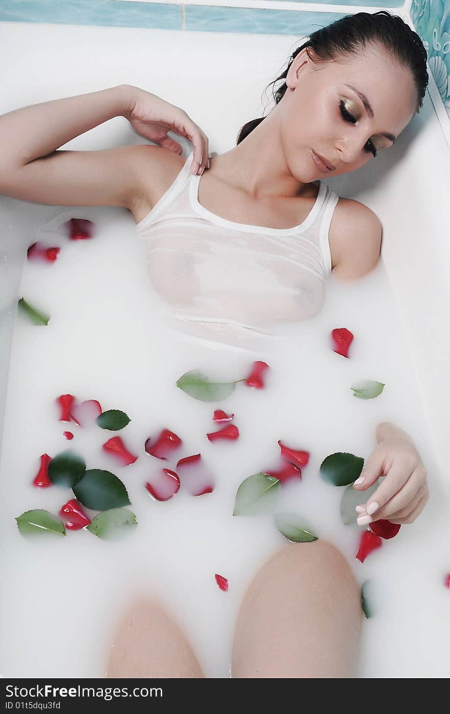 Beautiful woman relaxes in a bathroom with flowers