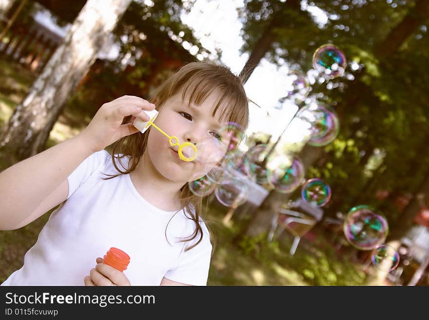 Little gir concentrated on blowing soap bubbles