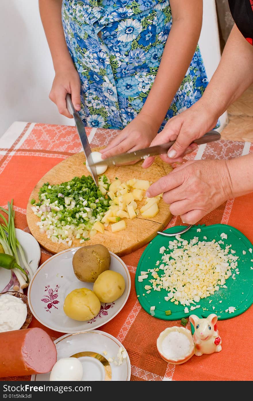 The grand daughter under the direction of the grandmother makes a dinner. The grand daughter under the direction of the grandmother makes a dinner.