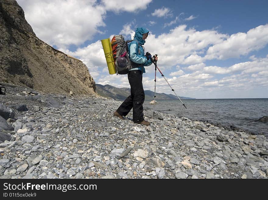 Woman backpacker goes on a coast. Lake Baikal, Eastern Siberia. Woman backpacker goes on a coast. Lake Baikal, Eastern Siberia