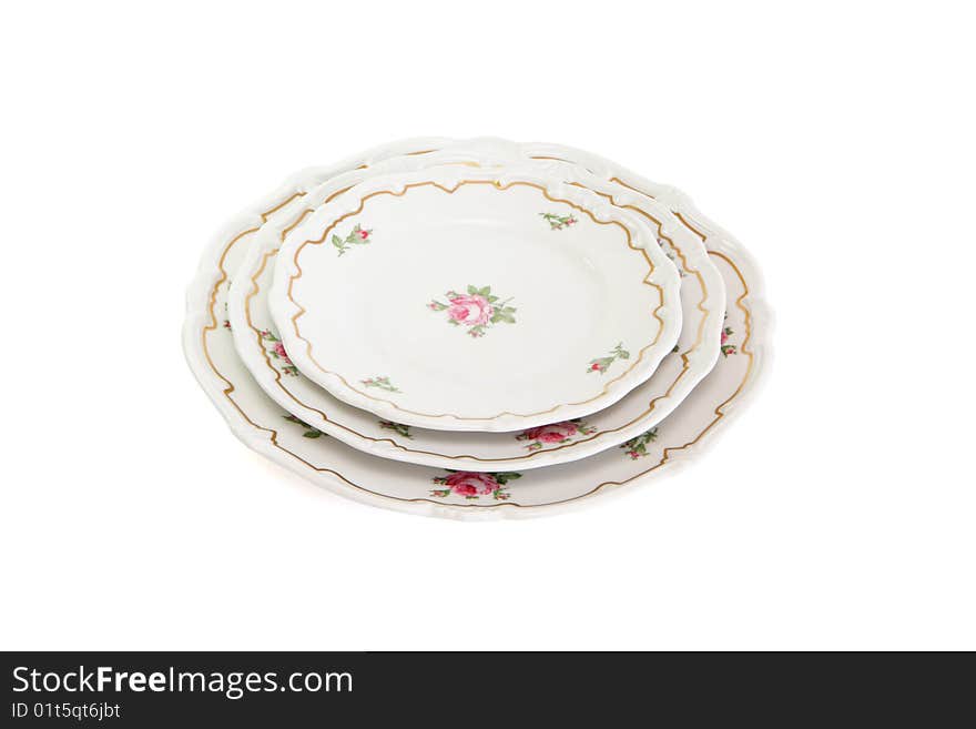 Stack of three white dinner plates and saucers with flowers and wavy rim isolated. Stack of three white dinner plates and saucers with flowers and wavy rim isolated