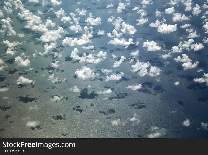 A group of single, isolated clouds on the water in this aerial viewfrom the Atlantic ocean.