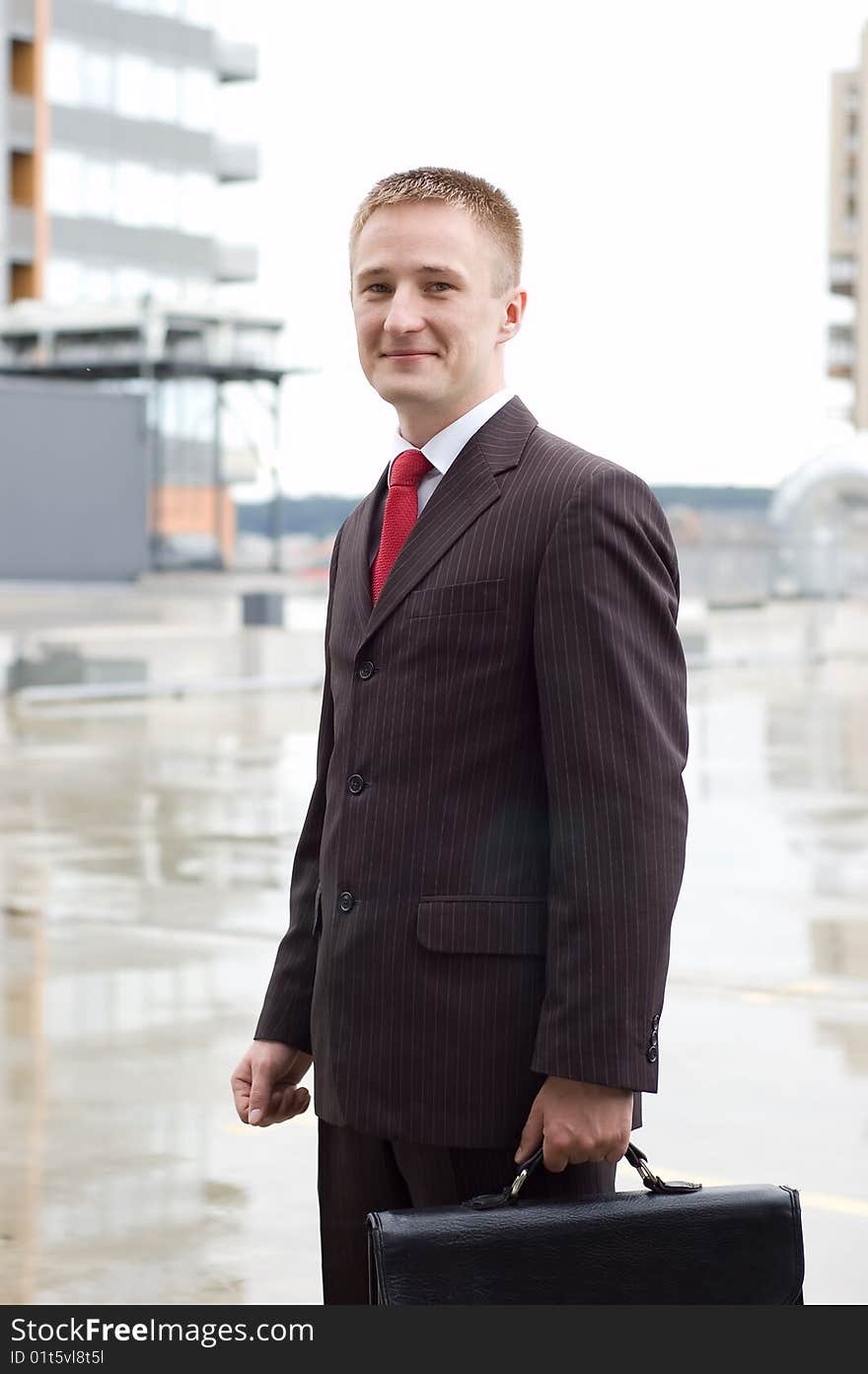 Portrait of a happy young businessman with case, smiling