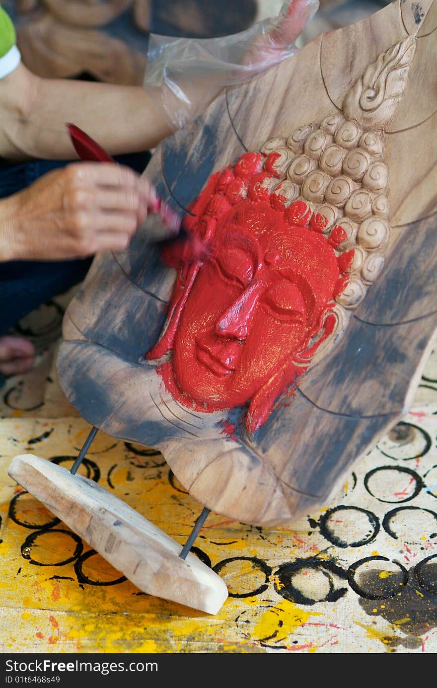 Hand painting the face of a Buddha image with red paint. Motion blur on the painting hand. Hand painting the face of a Buddha image with red paint. Motion blur on the painting hand.