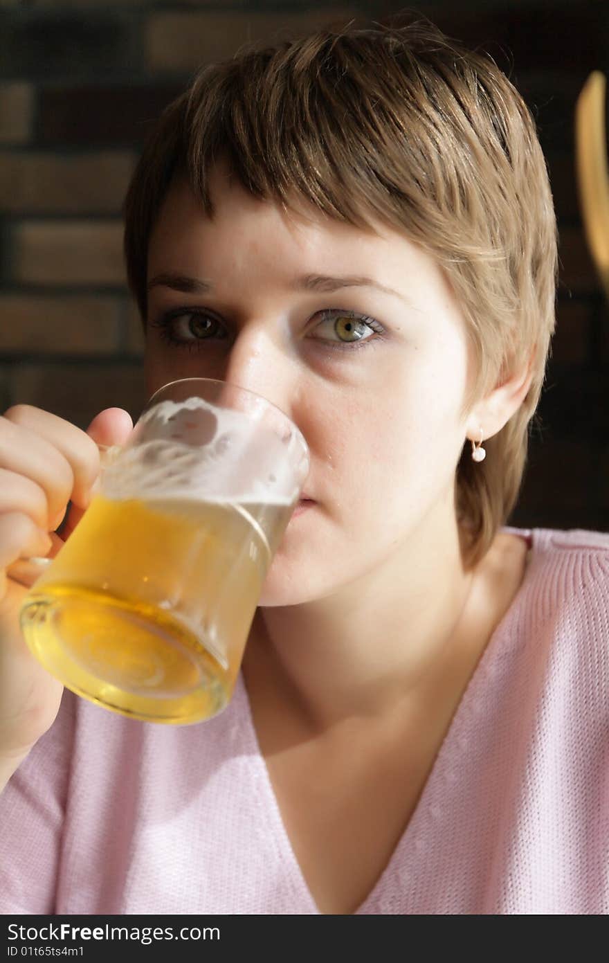 The young woman drinks a beer in a bar. The young woman drinks a beer in a bar