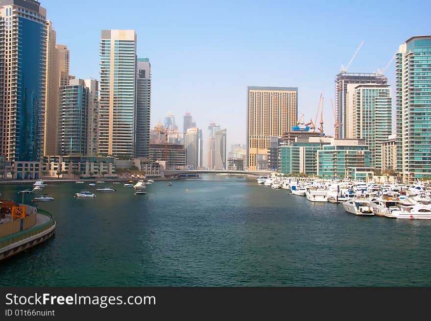 Several boats and yachts berthed in the Dubai Marina with luxury apartments in the background. Several boats and yachts berthed in the Dubai Marina with luxury apartments in the background