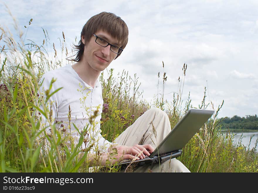 The man with laptop on green grass