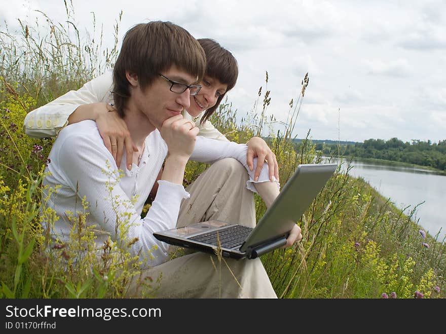 The man and women with laptop on green grass