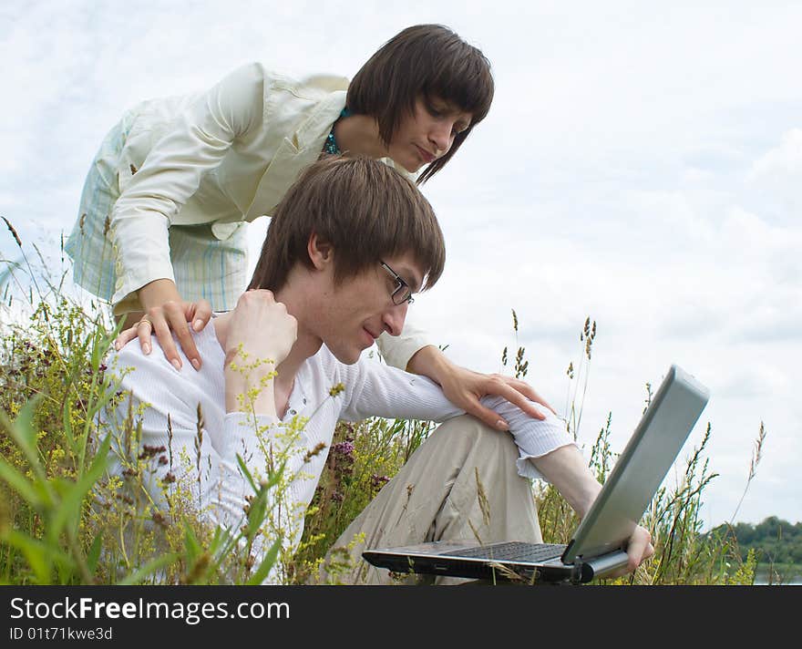 The man and women with laptop on green grass