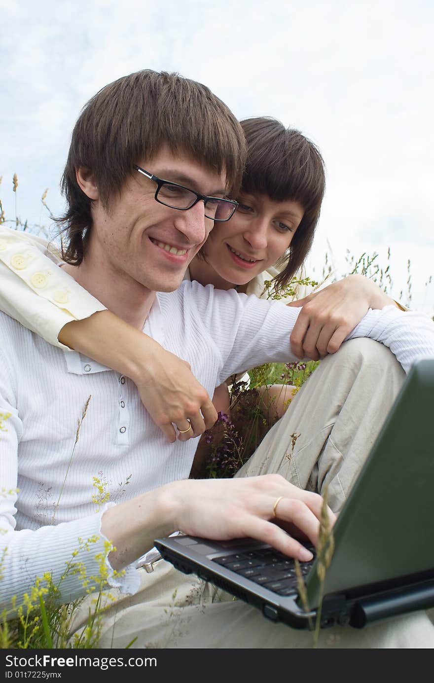 The man and women with laptop on green grass