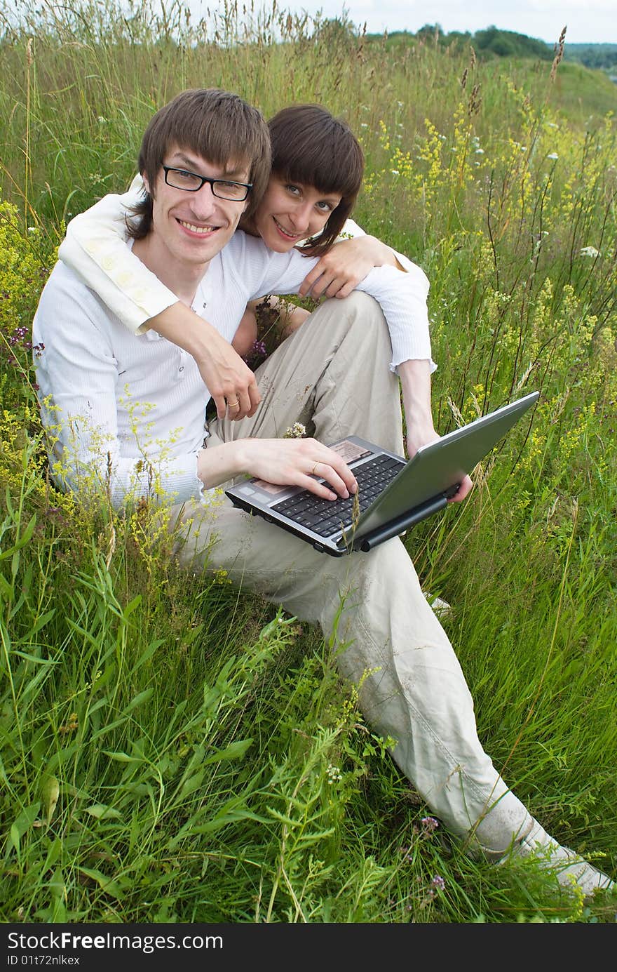 The man and women with laptop on green grass