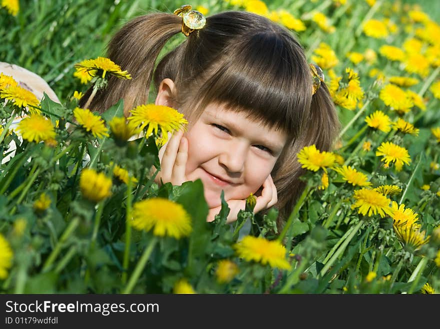 Little Cute Girl Is Lying On The Dandelion Meadow