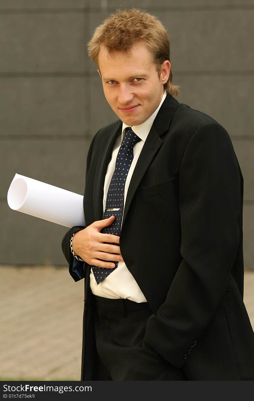 Happy businessman with bag and blueprint on the street