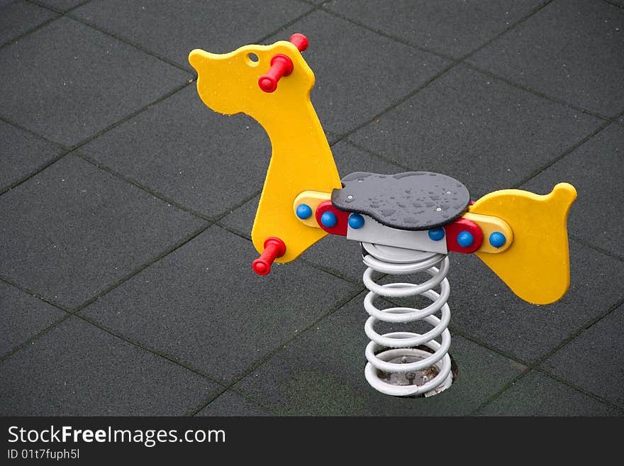 Yellow seesaw in rain shaped like animal on gray background