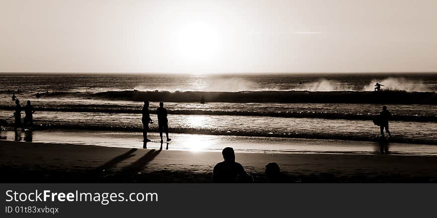 Beach scene as the sun sets and the surfers grab a last few waves. Beach scene as the sun sets and the surfers grab a last few waves