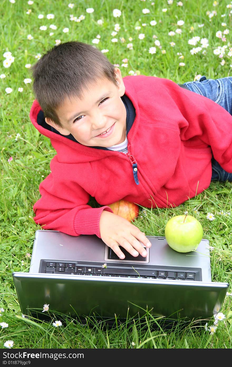 Cute little boy with laptop on a meadow. Cute little boy with laptop on a meadow