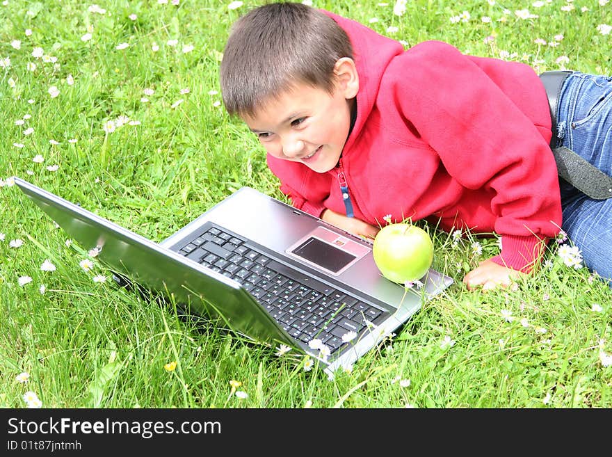 Cute little boy with laptop on a meadow