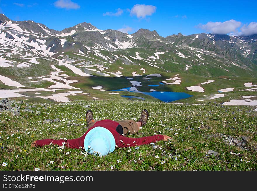 Hiker lies on meadow in mountains