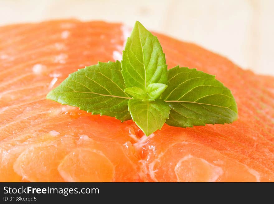 A piece of fresh raw salmon with basil leaves