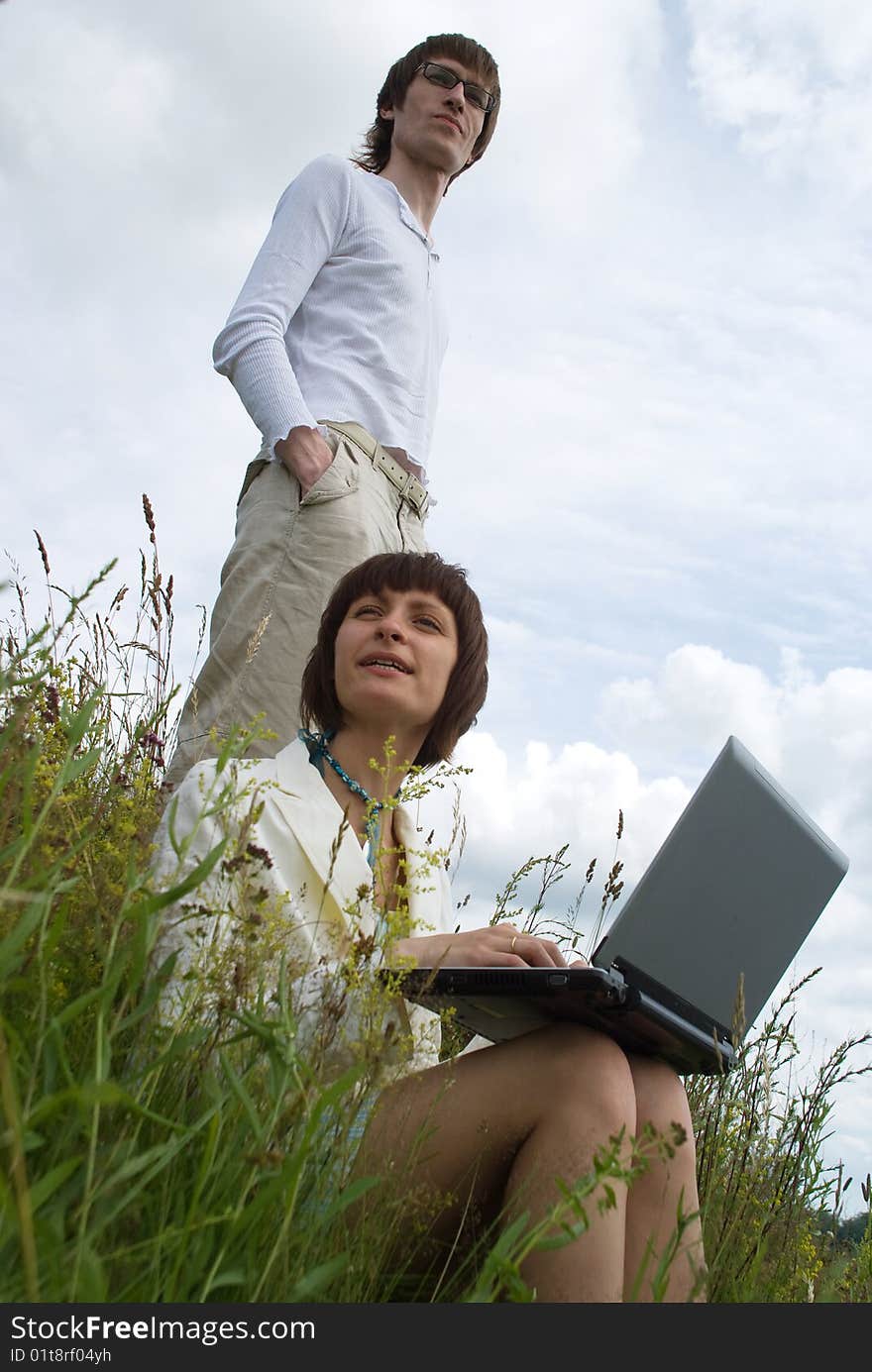 The man and women with laptop on green grass