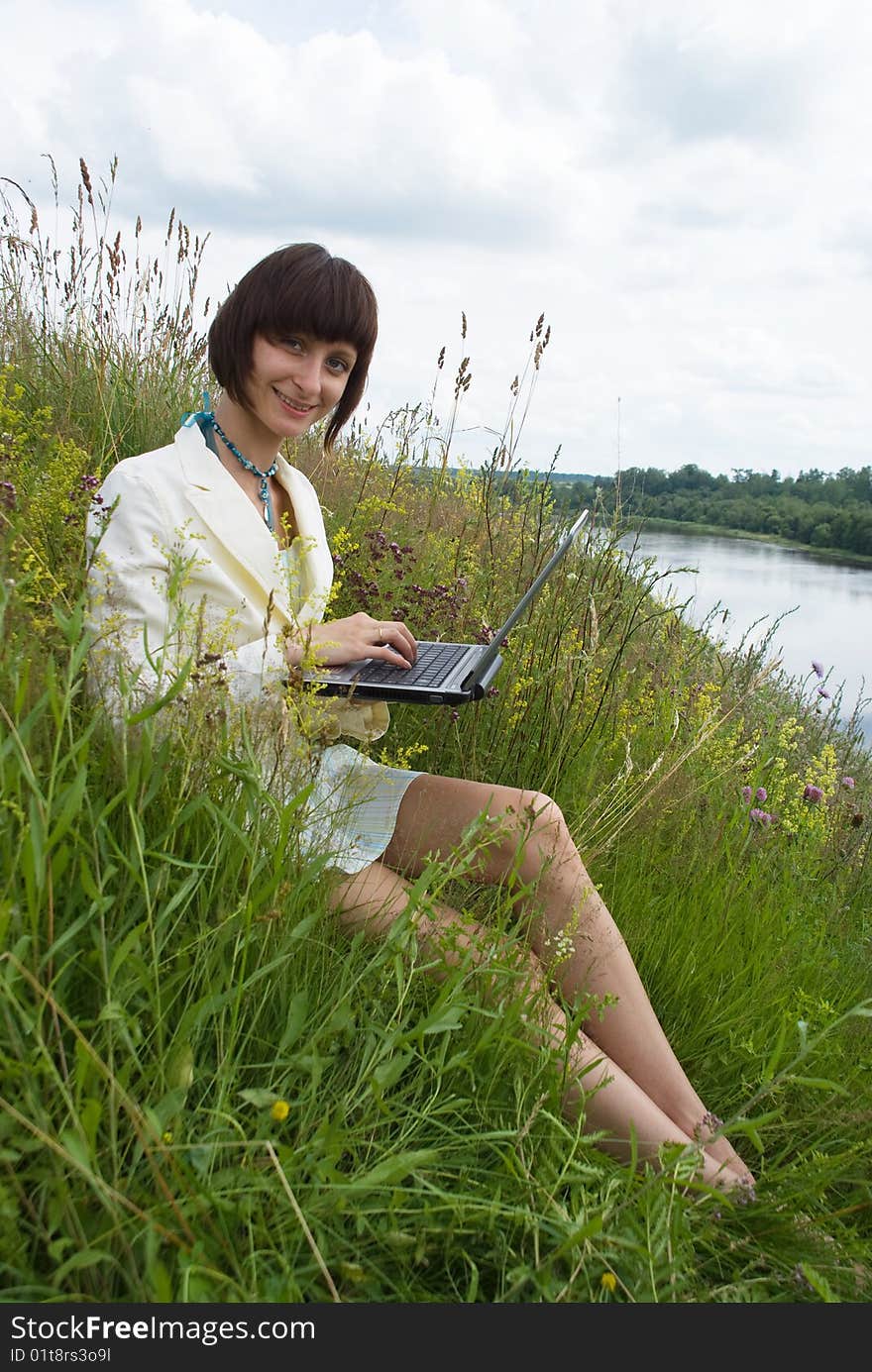 The woman with laptop on green grass