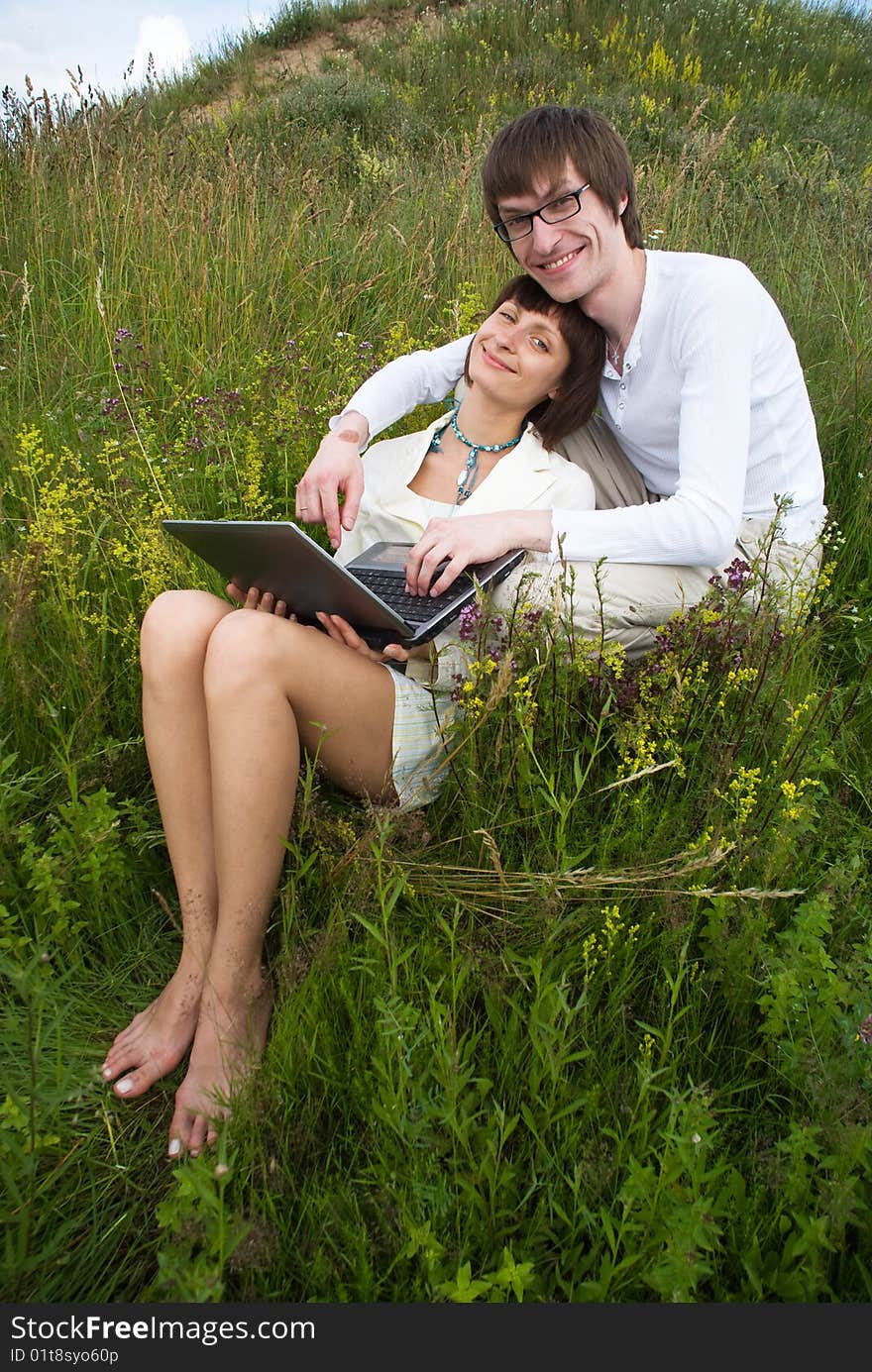 The man and women with laptop on green grass