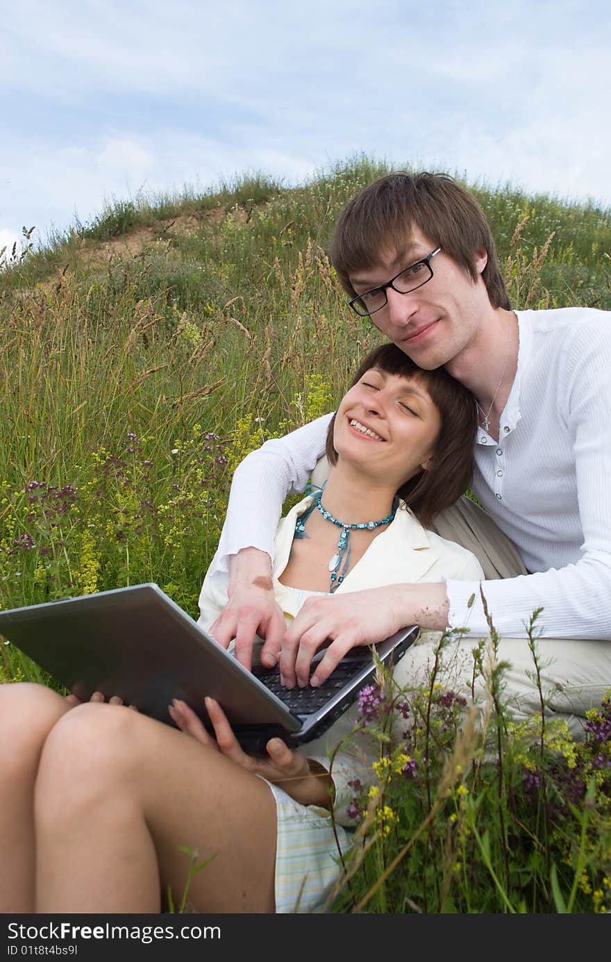 The man and women with laptop on green grass