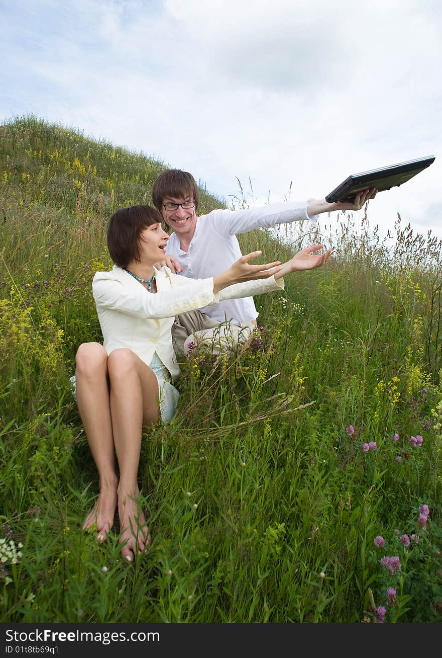 The man and women with laptop on grass