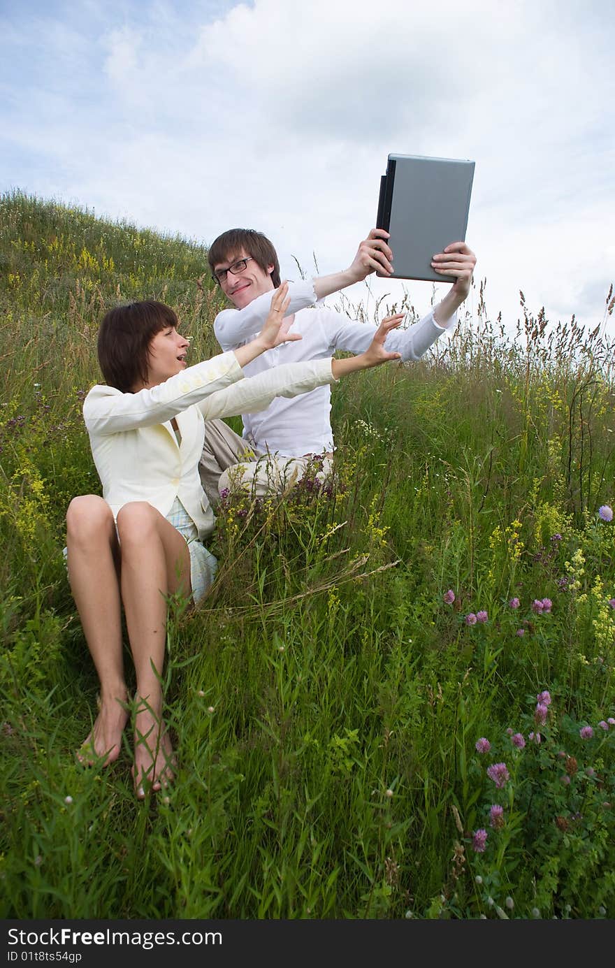 The man and women with laptop on grass