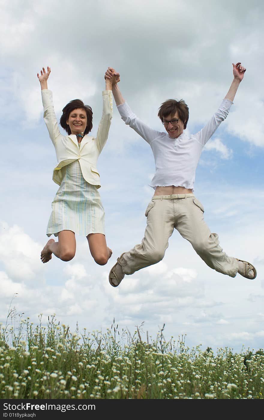 Jumping girl and boy on green meadow