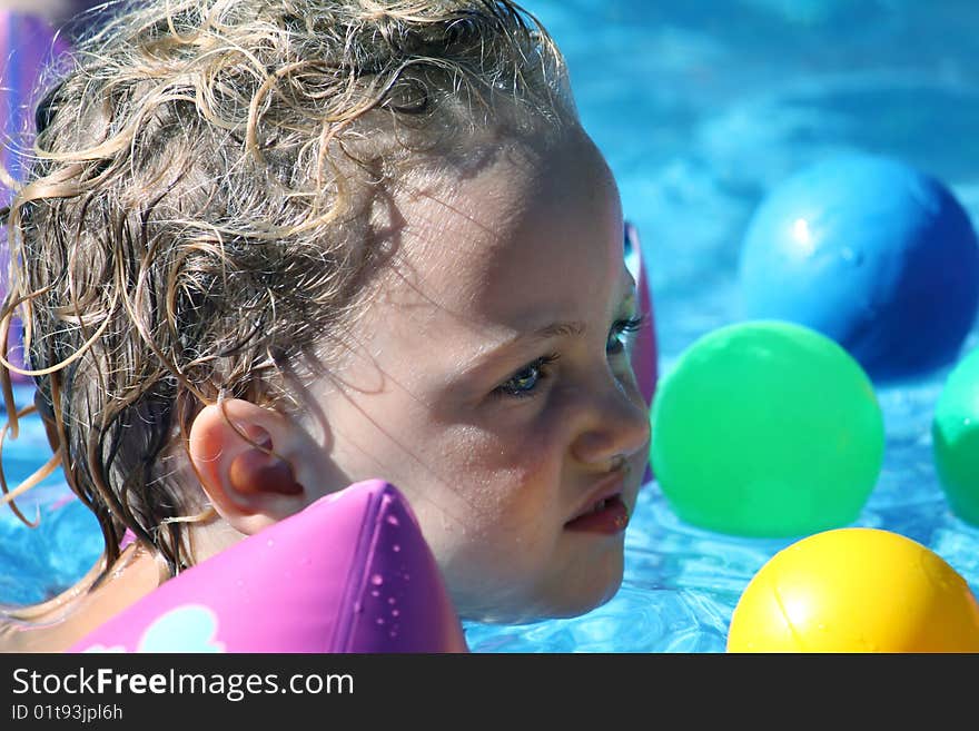 A small child swimming in a pool full of colorful balls. A small child swimming in a pool full of colorful balls