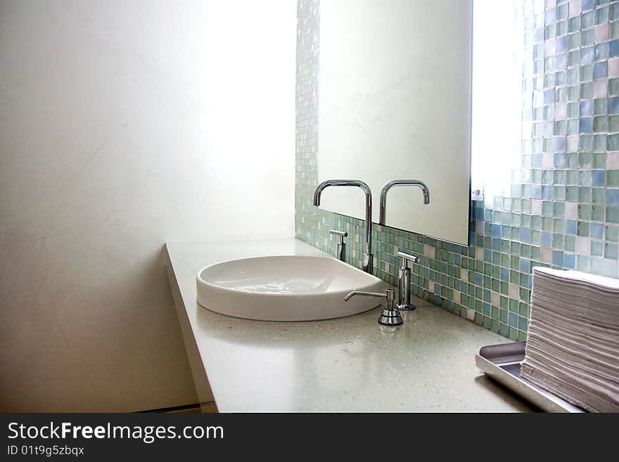 Detail of a bathroom at the clinic, showing a mirror, sink and tiles