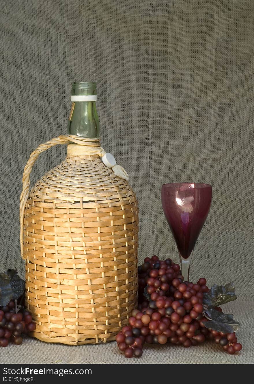 A still life with an antique jug or wine bottle with grapes and a glass, vertical with copy space. A still life with an antique jug or wine bottle with grapes and a glass, vertical with copy space