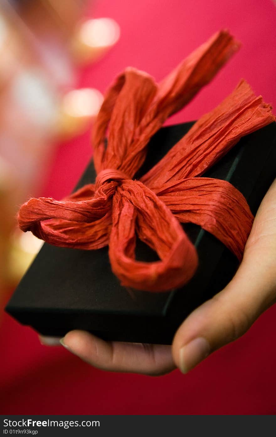 Hand holding gift with red bow